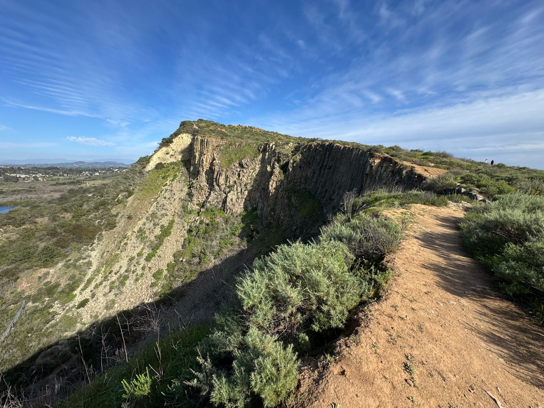Discover a stunning nature trail with rocky cliffs in Carlsbad, CA under a vibrant blue sky